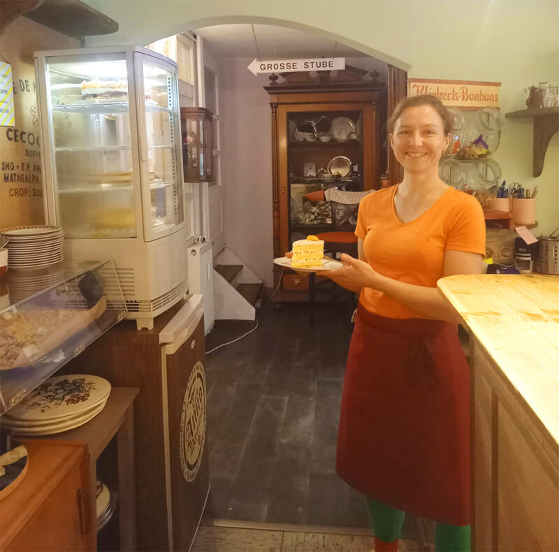 Gemütliches Café, freundliche Bedienung mit Kuchen und Kaffee, charmantes Ambiente im Vintage-Stil.